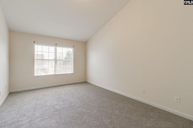 carpeted spare room featuring vaulted ceiling and baseboards