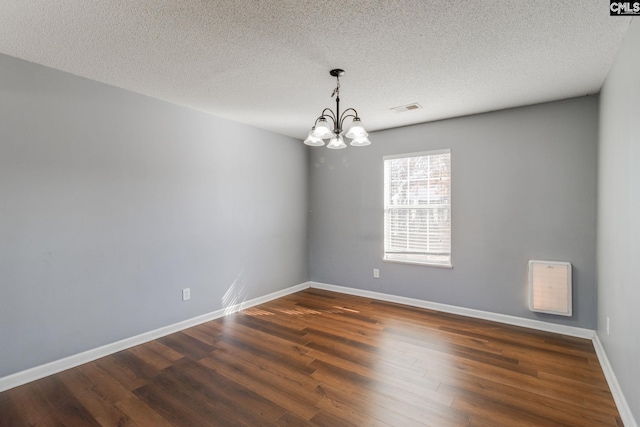 unfurnished room featuring a chandelier, dark wood-style flooring, baseboards, visible vents, and a textured ceiling