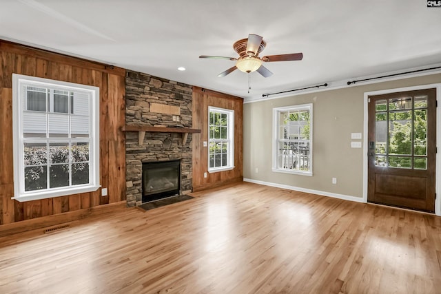 unfurnished living room with wooden walls, baseboards, a fireplace, and wood finished floors