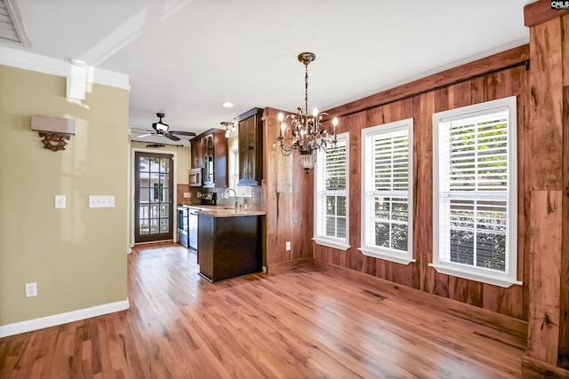 kitchen featuring appliances with stainless steel finishes, light countertops, light wood-style flooring, ceiling fan with notable chandelier, and baseboards