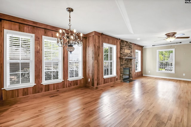 unfurnished living room with wooden walls, visible vents, and wood finished floors