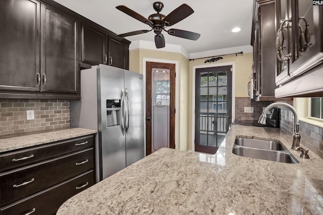 kitchen with ceiling fan, backsplash, a sink, stainless steel fridge with ice dispenser, and light stone counters