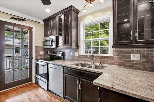 kitchen with plenty of natural light, a sink, light stone countertops, and stainless steel appliances