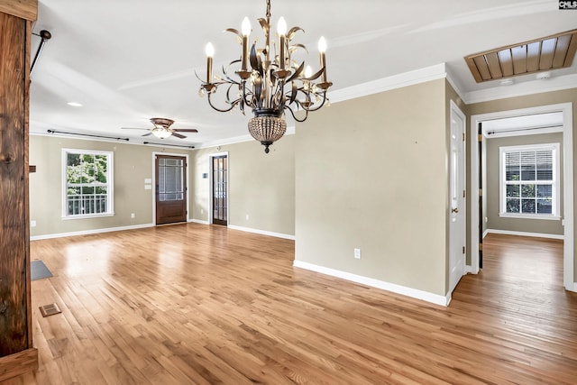 interior space with crown molding, light wood-style flooring, ceiling fan with notable chandelier, baseboards, and visible vents