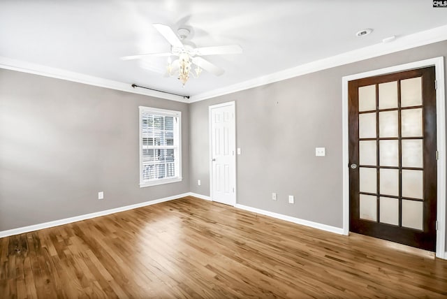 empty room with ceiling fan, baseboards, ornamental molding, and wood finished floors