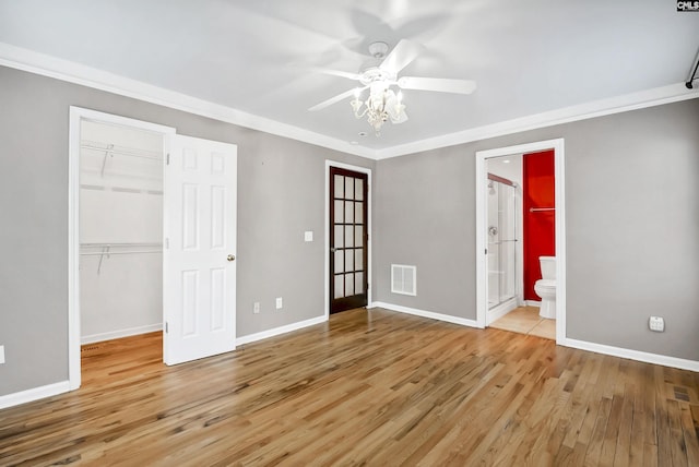 unfurnished bedroom with visible vents, a walk in closet, wood finished floors, and a closet