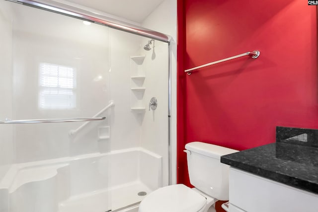 bathroom with toilet, a shower stall, and vanity