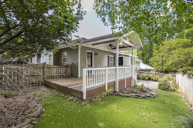 rear view of property with a ceiling fan, a fenced backyard, a yard, and a wooden deck