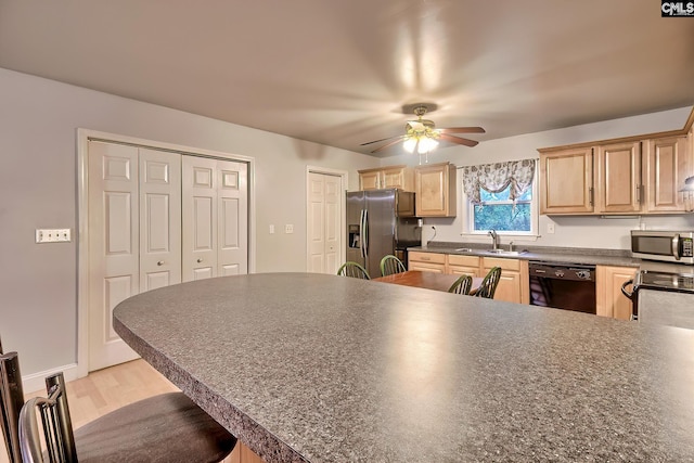 kitchen with a ceiling fan, light brown cabinetry, dark countertops, a sink, and stainless steel appliances