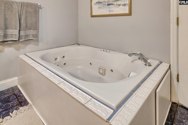 bathroom with a whirlpool tub and baseboards