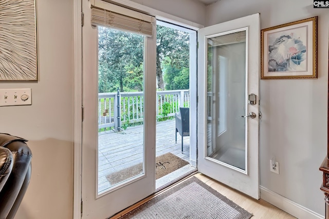 doorway to outside with baseboards and light wood-style flooring