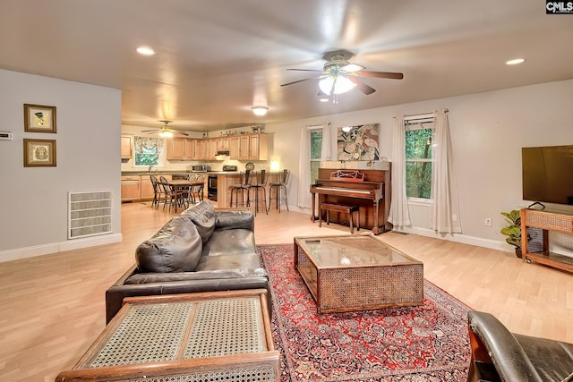 living area with light wood-type flooring, baseboards, ceiling fan, and visible vents