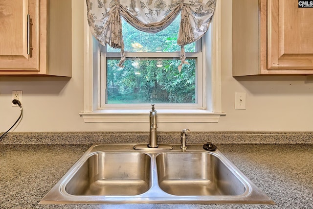interior details with a sink, light brown cabinets, and dark countertops