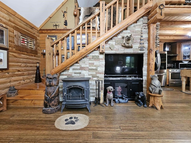living area with stairs, a high ceiling, wood finished floors, and a wood stove