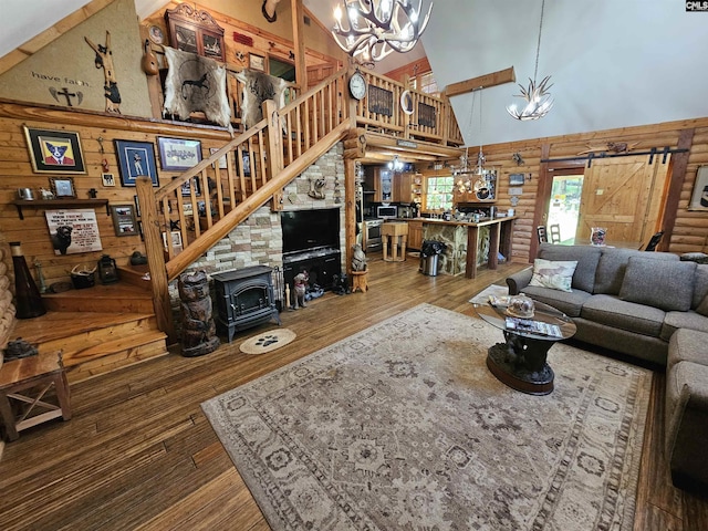 living room with a high ceiling, an inviting chandelier, stairs, rustic walls, and hardwood / wood-style flooring
