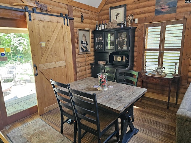 dining room featuring a barn door, rustic walls, and wood finished floors