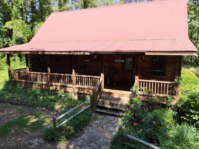 view of front of property featuring covered porch, log siding, and metal roof