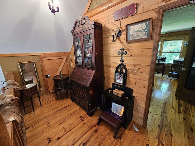 sitting room with light wood-style floors, wainscoting, and wooden walls