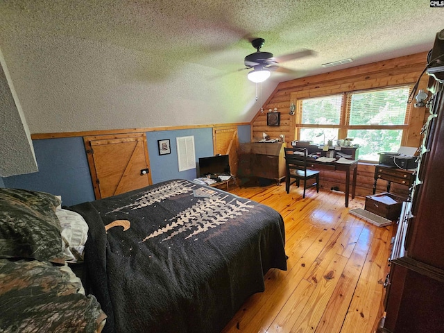 bedroom with visible vents, a textured ceiling, a ceiling fan, light wood finished floors, and vaulted ceiling
