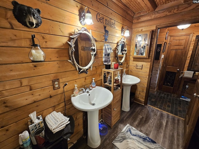 bathroom with a sink, wood walls, and wood finished floors