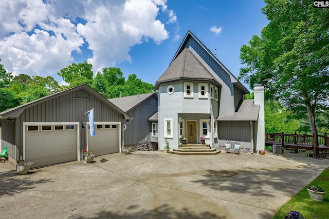 view of front of house with driveway, a shingled roof, a chimney, and board and batten siding