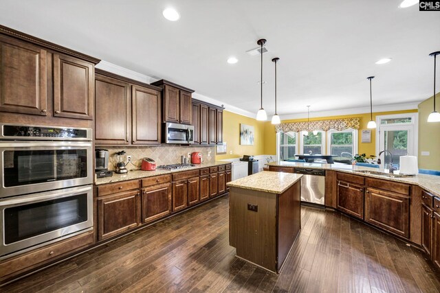 kitchen featuring washer and dryer, crown molding, a sink, stainless steel appliances, and a kitchen island