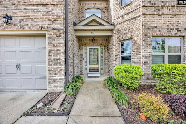 view of exterior entry with brick siding and a garage
