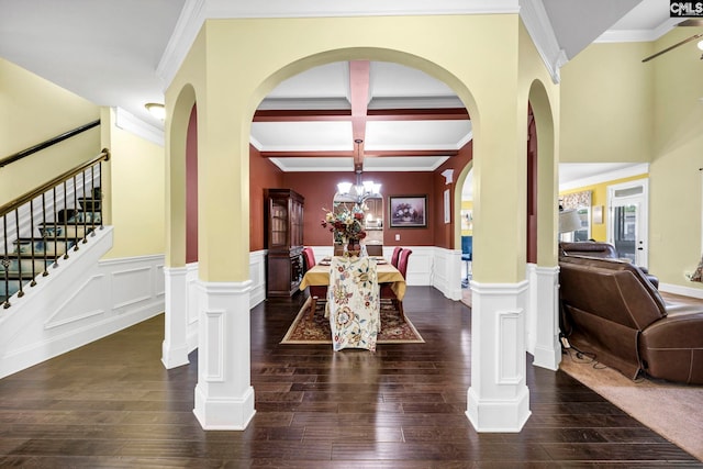 dining room featuring crown molding, arched walkways, a decorative wall, and a notable chandelier