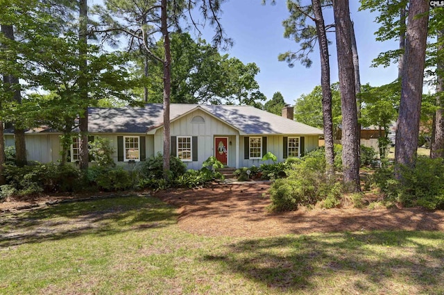 view of front of property featuring board and batten siding, a chimney, and a front lawn