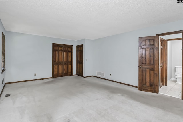 empty room with visible vents, a textured ceiling, baseboards, and light carpet