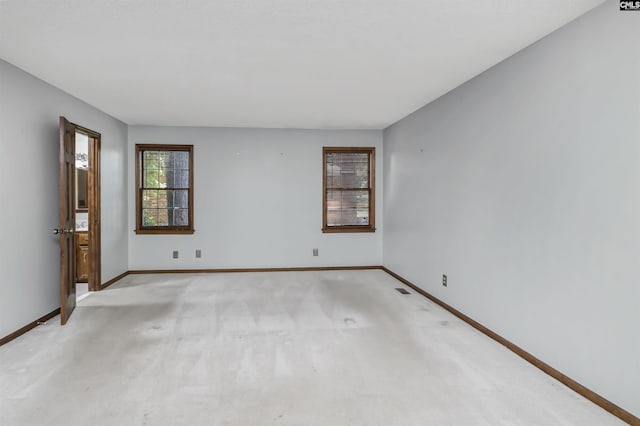 spare room featuring baseboards and light colored carpet