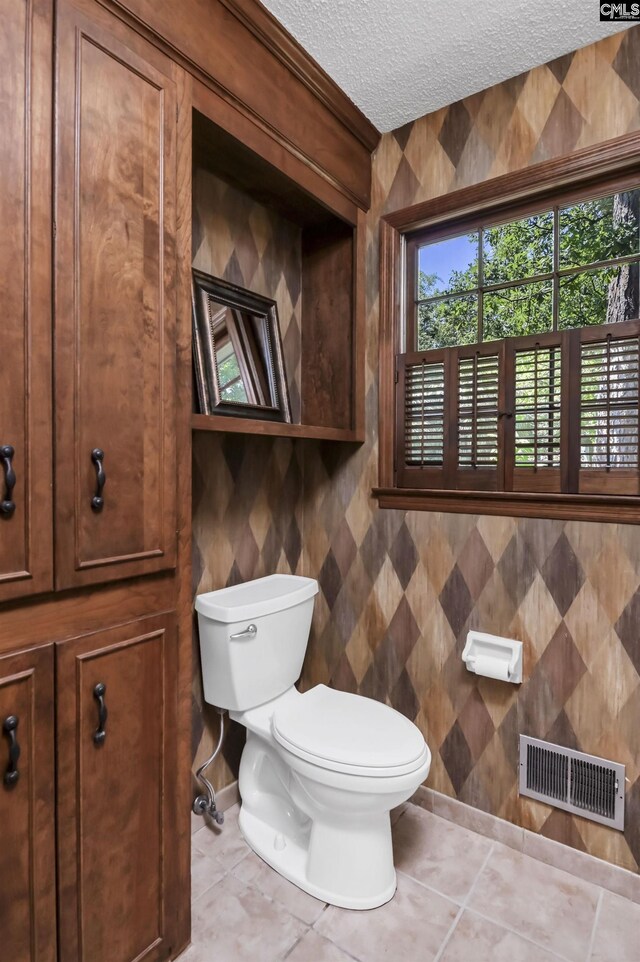 bathroom with toilet, tile patterned floors, visible vents, and a textured ceiling