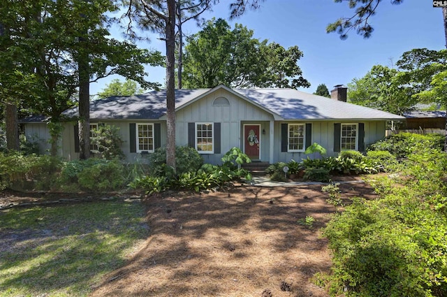 single story home featuring board and batten siding and a chimney