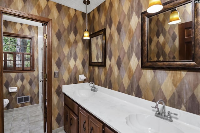 bathroom featuring a sink, toilet, double vanity, and visible vents