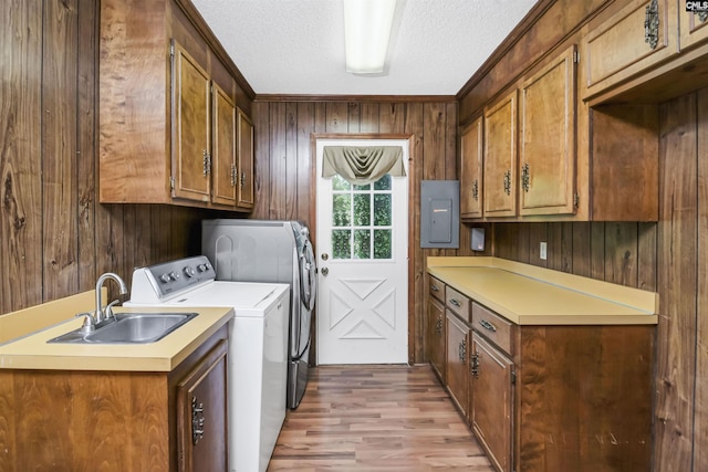 washroom with cabinet space, a sink, light wood finished floors, separate washer and dryer, and wood walls