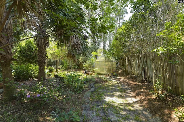view of yard with an outdoor structure, fence, and a greenhouse