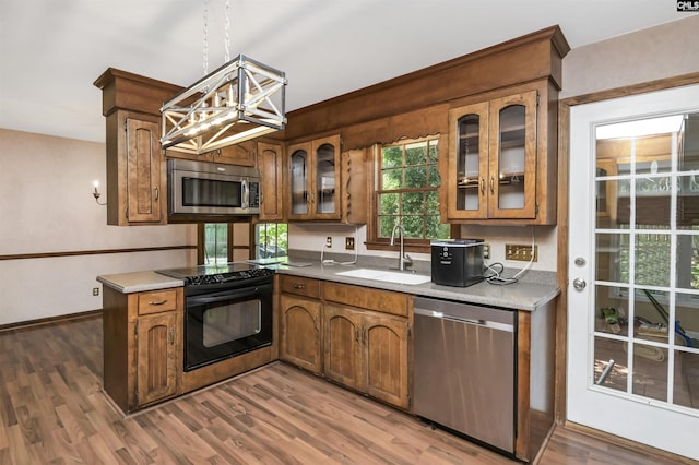 kitchen with wood finished floors, light countertops, a sink, appliances with stainless steel finishes, and a notable chandelier