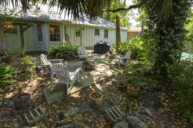 back of property with a patio, board and batten siding, and an outdoor fire pit