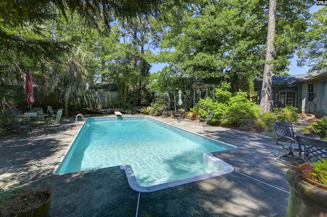 outdoor pool featuring a diving board, a patio area, and a fenced backyard