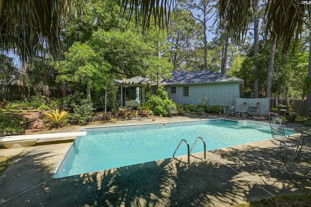 view of pool with a fenced in pool, a diving board, fence, and a patio