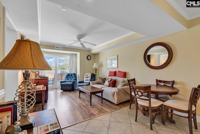 living area with visible vents, a ceiling fan, crown molding, and light tile patterned floors