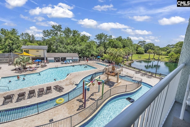 community pool featuring fence, a patio, and a water view