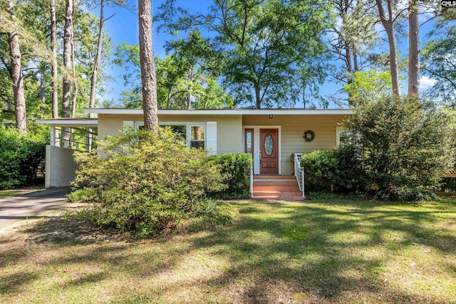 view of front facade featuring brick siding, driveway, a front yard, and an attached carport
