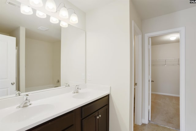 bathroom featuring double vanity, a sink, visible vents, and a spacious closet