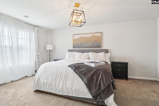 carpeted bedroom featuring a chandelier, baseboards, and visible vents