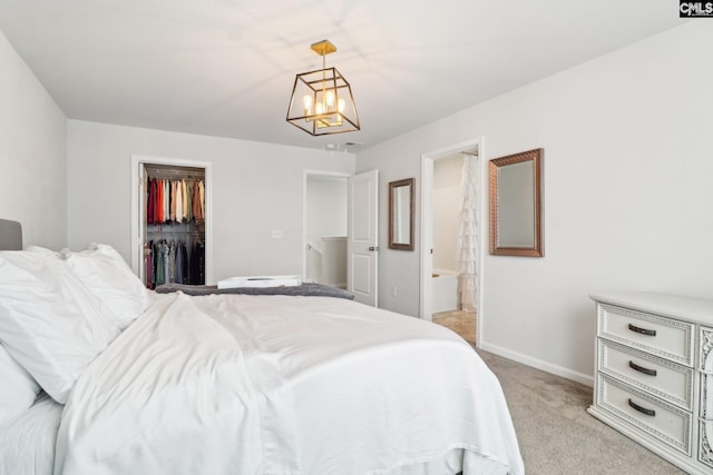 bedroom featuring a closet, light carpet, baseboards, a walk in closet, and a chandelier