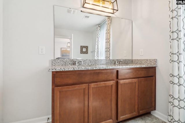bathroom with double vanity, baseboards, visible vents, and a sink