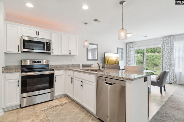 kitchen with white cabinets, light stone counters, a sink, stainless steel appliances, and a peninsula