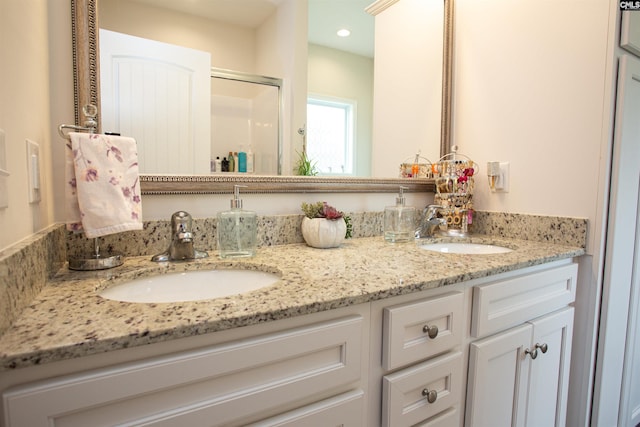 full bath featuring a sink, a stall shower, and double vanity