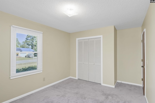 unfurnished bedroom featuring a closet, carpet flooring, a textured ceiling, and baseboards